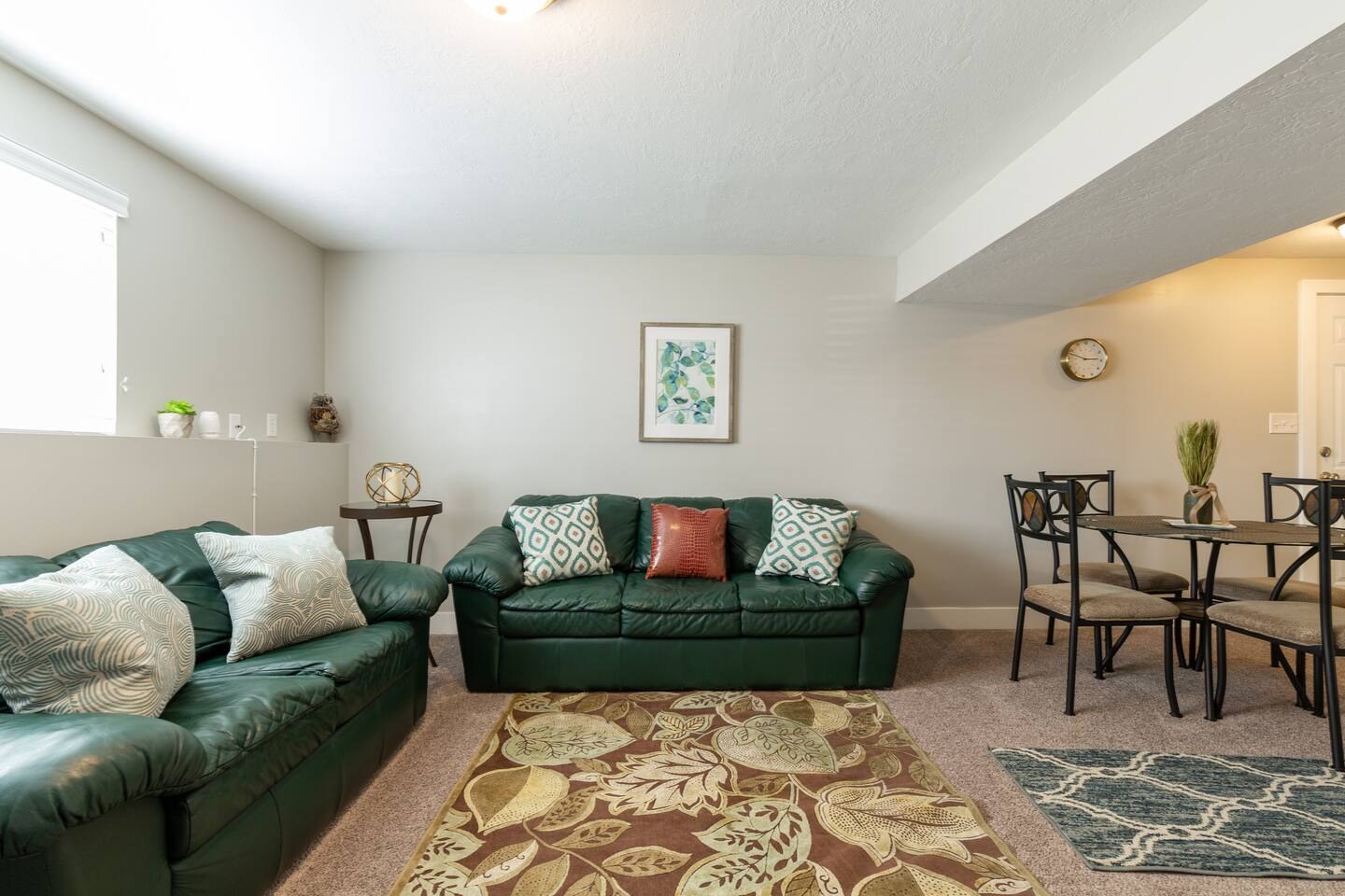 Living room with green sofas and a nearby dining area